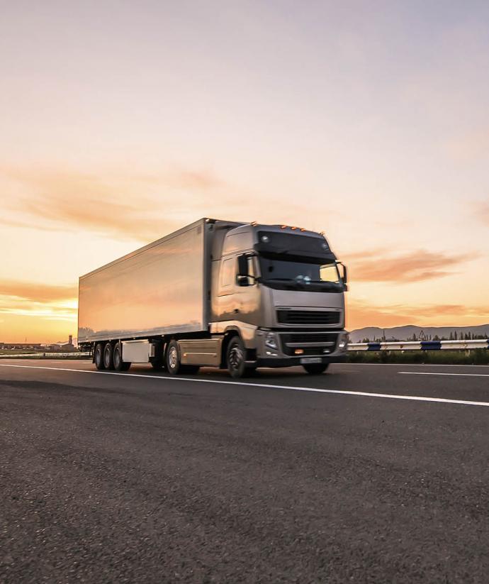 Rijdende vrachtwagen met wegtransport op snelweg met zonsondergang | Seacon Logistics